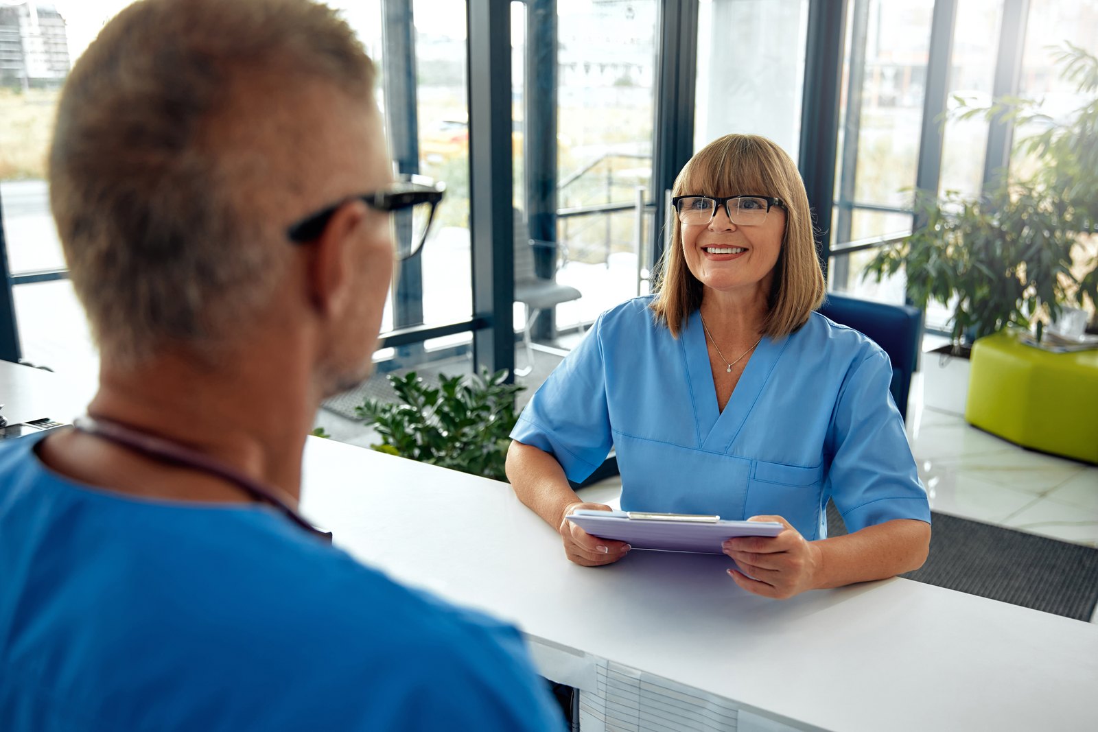 tilt-healthcare-success-cbx69774672 Medical receptionist assisting a patient at the front desk